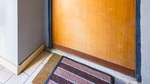 Una porta de fusta amb un pom d'or i una clau, situada en un angle amb una paret blanca i un sòcol marró.