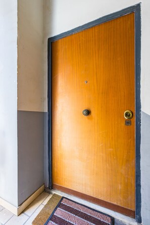 A wooden door with a brass doorknob and a keyhole, set in a corner with a white wall and a brown baseboard. - PizzArcHouse - One Bedroom Apartment, Sleeps 4 (Naples)