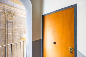 A wooden door with a keyhole and a lock, adjacent to a stone wall with a window and a metal railing. - PizzArcHouse - One Bedroom Apartment, Sleeps 4 (Naples)