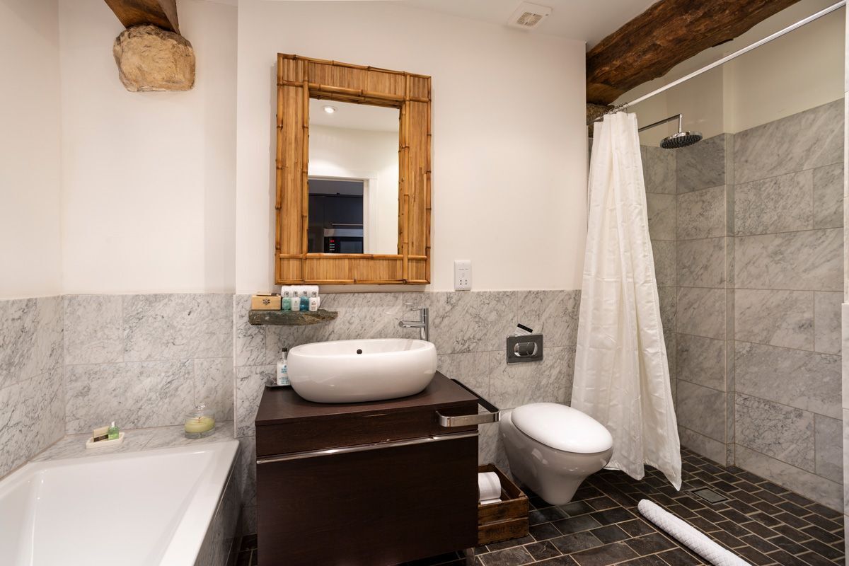 A bathroom with a bathtub, a sink, a toilet, and a shower area.