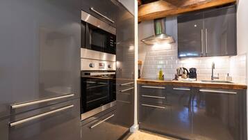 Een moderne keuken met roestvrijstalen apparatuur, houten balken en een witte tegelwand.