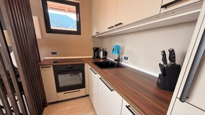 Una cocina compacta con horno integrado, un lavamanos y un bloque para cuchillos.