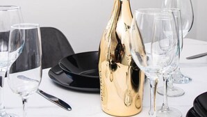 Ett bord med en flaska champagne, glas och en svart tallrik.