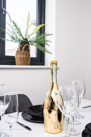 A table with a bottle of champagne, glasses, and a black plate. - Treetop View by MyCityHaven (Redland)