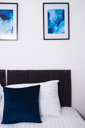 A bed with a dark headboard, two pillows, and two framed abstract paintings on the wall above. - Treetop View by MyCityHaven (Redland)
