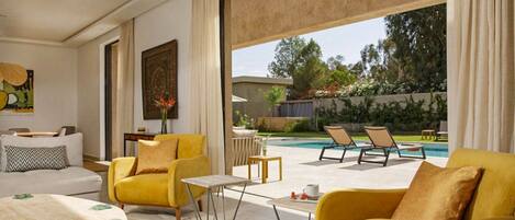 A modern living room with yellow sofas, a coffee table, and a view of a swimming pool.