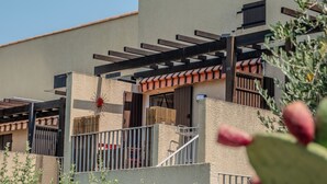Ein Gebäude mit einer Pergola, einer roten Blume und einem Kaktus im Vordergrund.