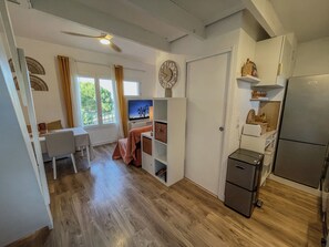 A compact living space with a kitchenette, a dining area, and a bedroom with a window. - Charming studio with terrace near the beaches (Hyères)