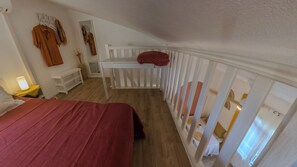 Ein Schlafzimmer mit einem Bett, einem Nachttisch, einem Schreibtisch und einem weißen Geländer.