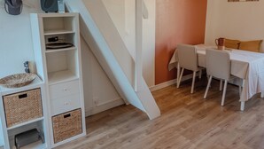 Ein Zimmer mit einer weißen Treppe, einem Esstisch mit Stühlen und einer Wand mit großem Bogenmuster.