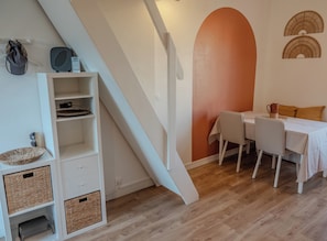 Ein Zimmer mit einer weißen Treppe, einem Esstisch mit Stühlen und einer Wand mit großem Bogenmuster.