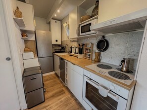 A modern kitchen with stainless steel appliances, wooden countertops, and a microwave above the stove. - Charming studio with terrace near the beaches (Hyères)