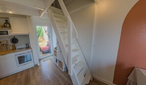 A kitchen with a built-in oven, a microwave, and a sink. There is a staircase leading to an outdoor area. - Charming studio with terrace near the beaches (Hyères)