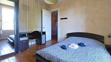 Un dormitori amb un llit, una taula de treball i una cadira.