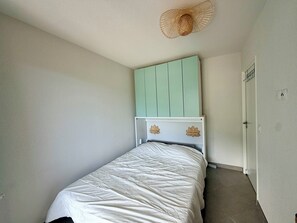 A bedroom with a bed, a light green headboard, a white wall, and a door. - New and quiet apartment close to the city center (Briançon)