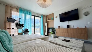 Una sala de estar moderna con un sofá, un televisor y un balcón con plantas.