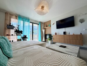 A modern living room with a sofa, a TV, and a balcony with plants. - New and quiet apartment close to the city center (Briançon)