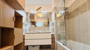 Un baño moderno con cabina de ducha de vidrio, muebles de madera y tocador con espejo.