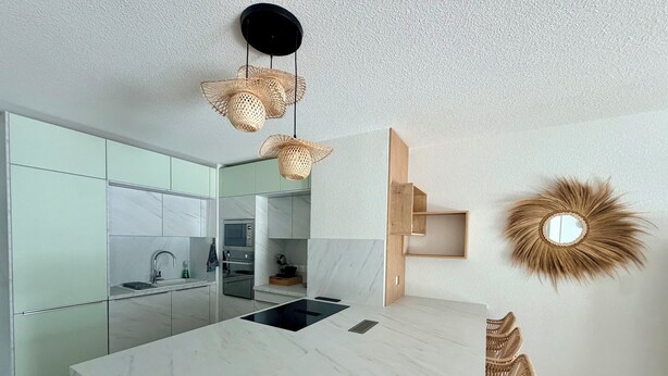 Una cocina moderna con encimera de mármol, electrodomésticos integrados y un estante original de pared.