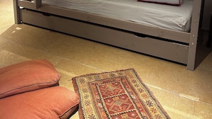 Een stapelbed met een matras, kussens en een opbergkist.