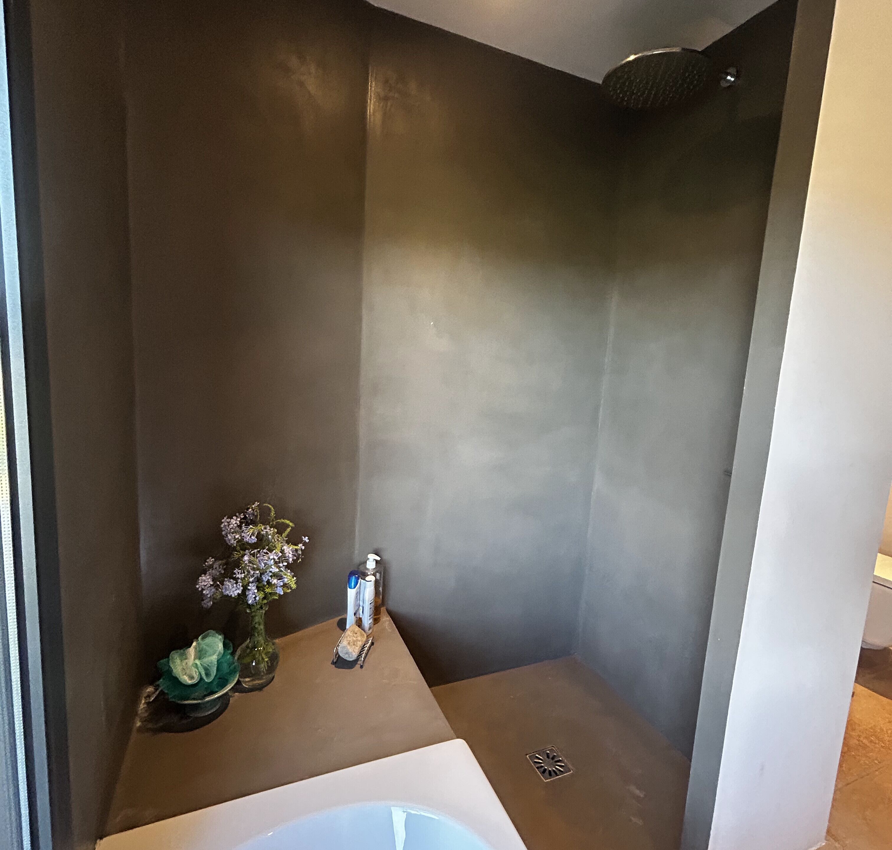 A bathroom with a bathtub, a small table with toiletries, and a shower area.