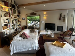 A living room with two beds, a bookshelf, a TV, and a view of the outdoors. - Villa with pool and panoramic views in Ollioules (Ollioules)