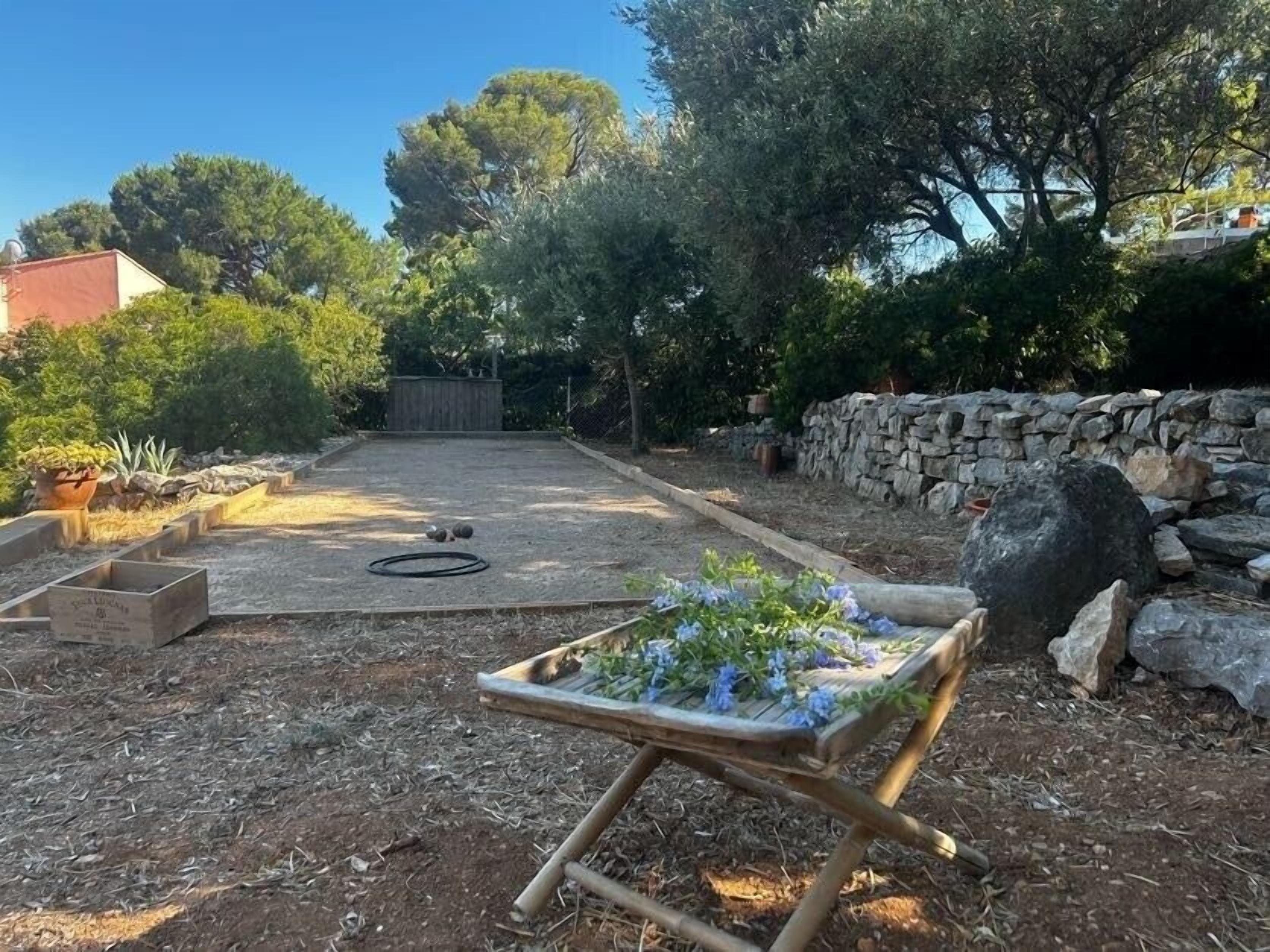 A garden area with a wooden bench, a stone wall, and a variety of plants.