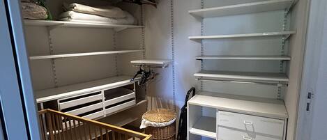 A storage room with shelves, a wicker basket, and a baby crib.