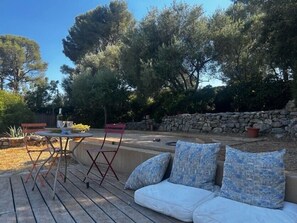 Un espace extérieur aménagé avec un mur en pierre, une terrasse en bois et une petite piscine.