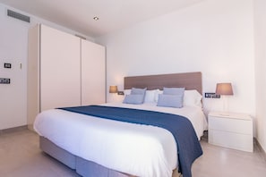 Ein Schlafzimmer mit einem Bett, Nachttischen, einem Kleiderschrank und einem Kopfteil.