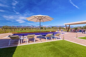 A swimming pool with lounge chairs and an umbrella, surrounded by a well-maintained lawn and a view of mountains. - Villa Pareteta - Three Bedroom Villa, Sleeps 6 (Binissalem)