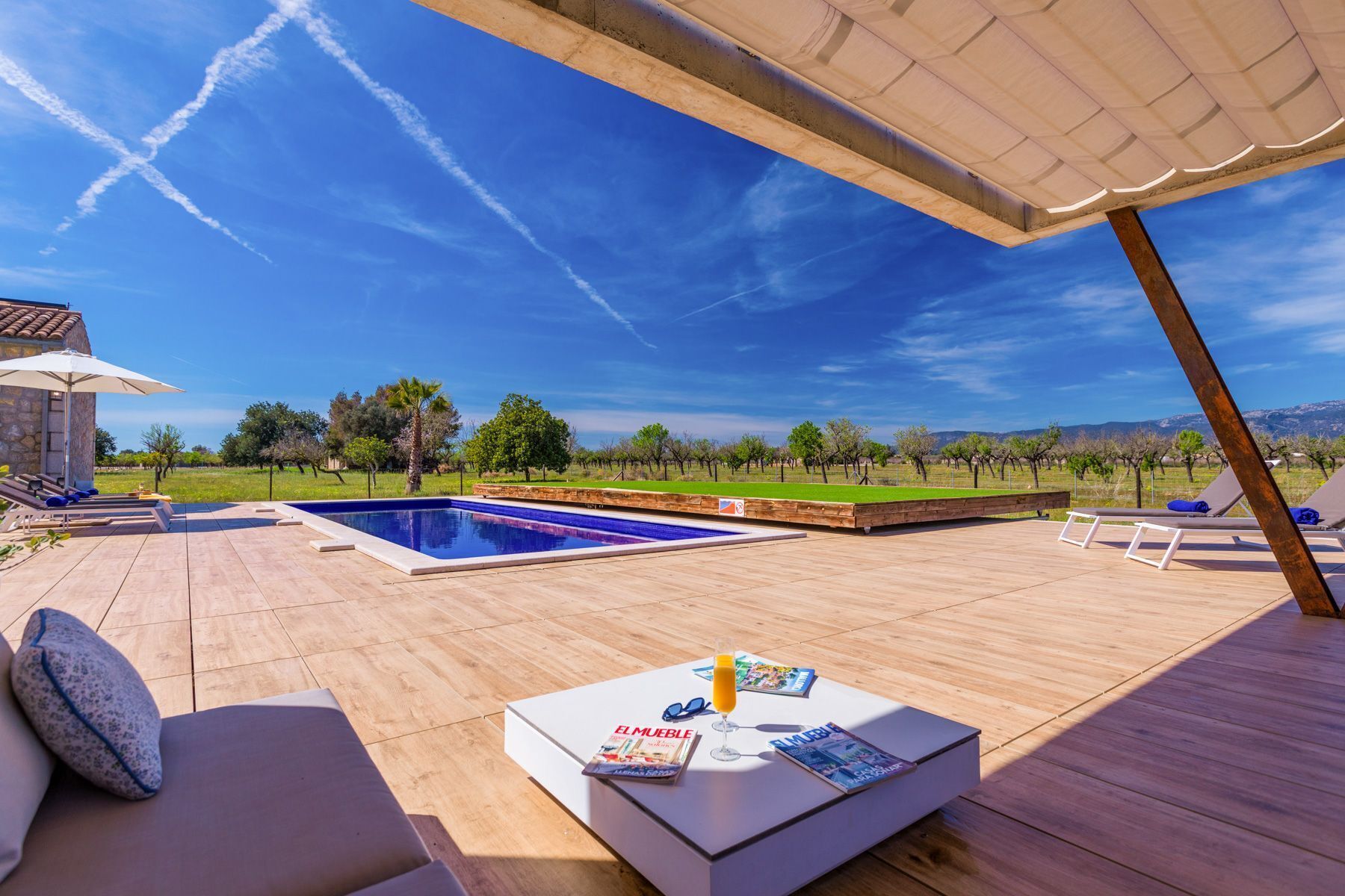 Ein Poolbereich mit Liegestühlen, einem Tisch mit Zeitschriften und einem Getränk, und Blick auf einen Weinberg.