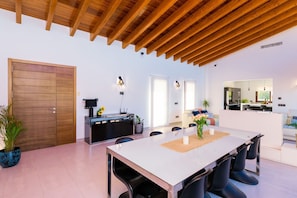 Une cuisine moderne avec un coin repas, des poutres en bois au plafond et une grande porte en bois.