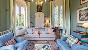 A spacious living room with a large sofa, two armchairs, a coffee table, and a chandelier.