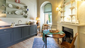 A kitchen with a sink, cabinets, and a dining area with a table and chairs.