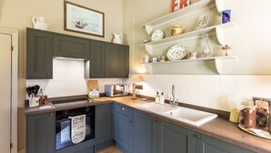 A kitchen with dark cabinets, a wooden countertop, a sink, and a stove.