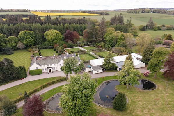 A large estate with multiple buildings, a pond, and surrounding fields.