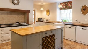 Una cocina con encimera de madera, espacio para vinos empotrado y microondas.