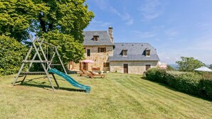 Ein Haus aus Stein mit einem Rasen, einer Holz-Schaukel und einem Picknicktisch.