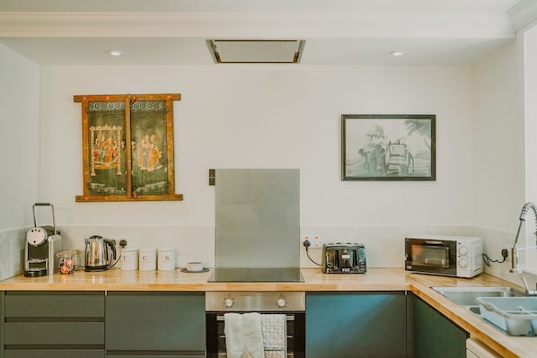 Eine moderne Küche mit Kühlschrank, Mikrowelle, Toaster und Wasserkocher. Es sind Schränke und ein Spülbecken vorhanden.