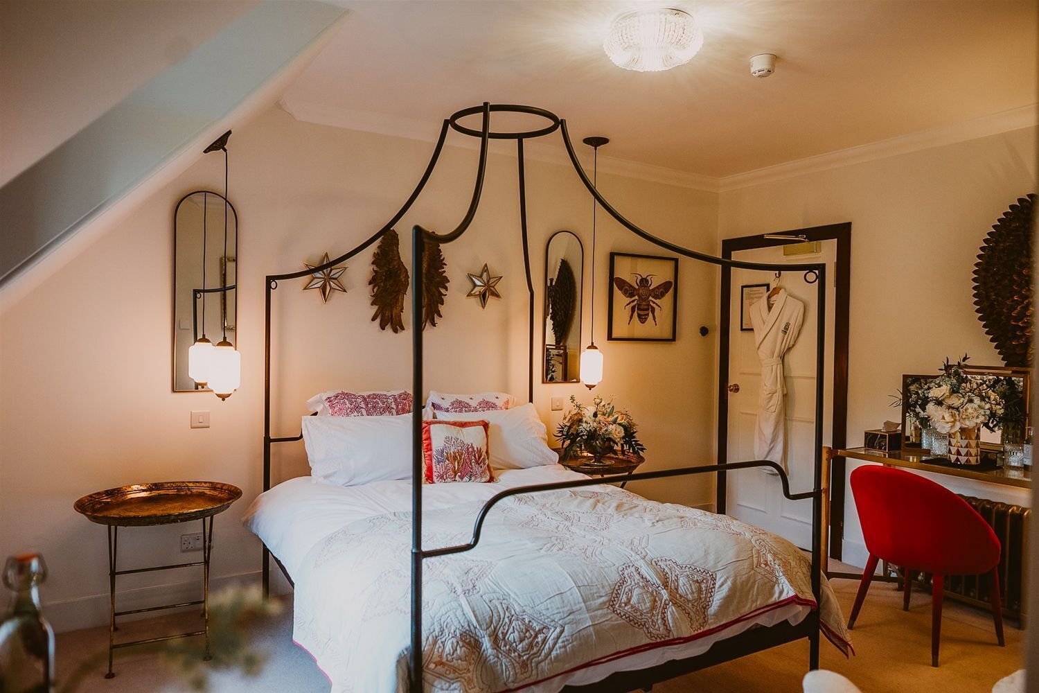 Un lit à baldaquin, une table de chevet, une chaise et un miroir.