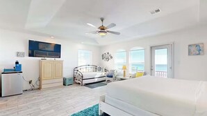 Une chambre à coucher avec un lit, un ventilateur de plafond, une télévision, une armoire et une vue sur l’océan.