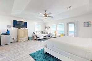 Ein Schlafzimmer mit Bett, Deckenventilator, Fernseher, Kleiderschrank und Meerblick.