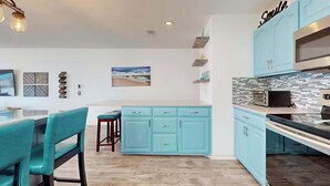 Une cuisine moderne avec des armoires de couleur turquoise, un comptoir noir et un four à micro-ondes en acier inoxydable.