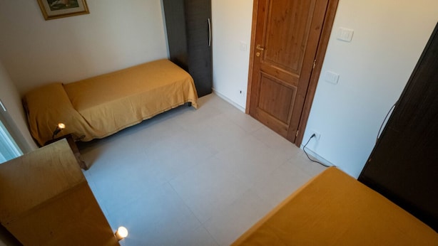 A small, single-bed room with a wooden door and a framed picture on the wall. - GuestHost - Lisignano Cozy Apartment with Parking (Gazzola)