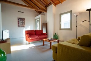 Una sala de estar con un sofá rojo, un sofá amarillo, una mesa de centro de madera y un jarrón verde.