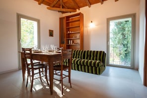 A dining area with a wooden table and chairs, a striped sofa, and a built-in bookshelf.