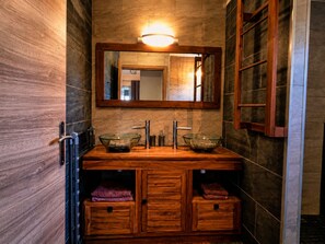 Ein Badezimmer mit Waschtisch aus Holz, zwei Waschbecken aus Glas, einem Spiegel und einem Handtuchhalter.