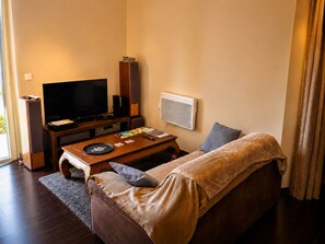 Ein Wohnzimmer mit Flachbildfernseher, Couch, Couchtisch und Soundsystem.