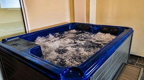 A hot tub with a blue exterior, filled with water and bubbles, indicating it is in use. - Phenomenal 1-bedroom apartment with private Jacuzzi and pool (Le Tampon)